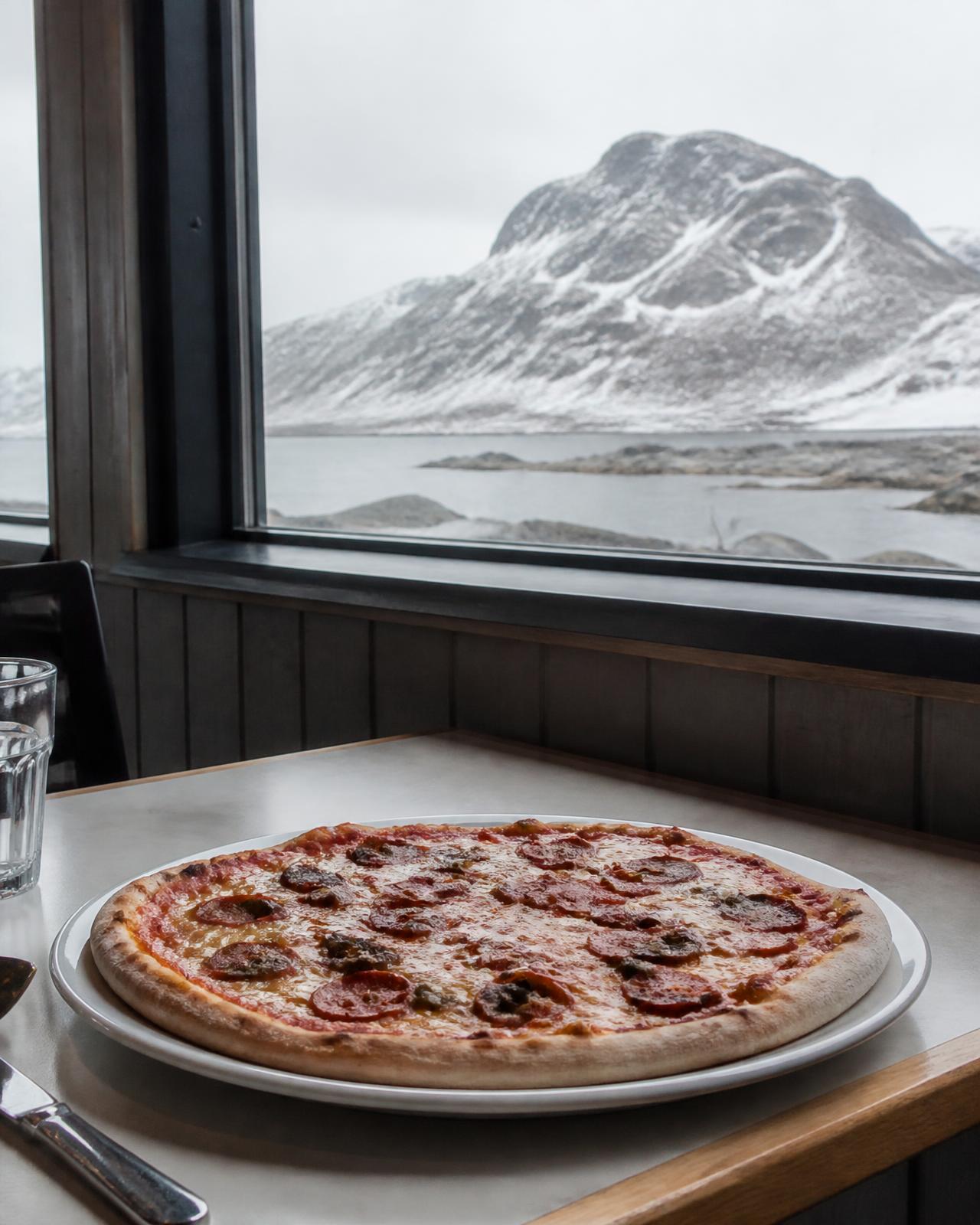 Pizza på et bord ved vinduet med udsigt til fjeldet